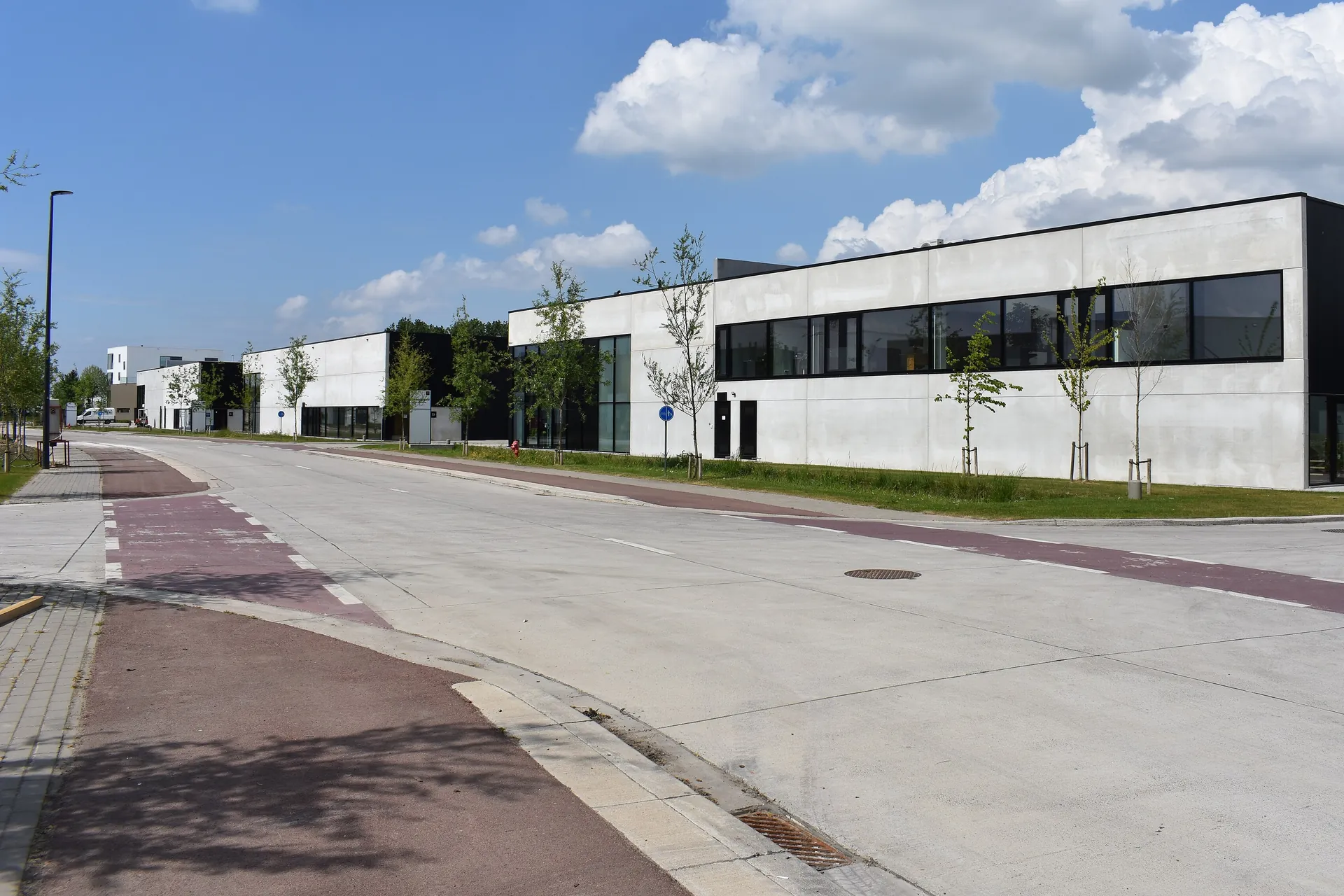 Nouveaux halls d'entreprise à toiture plate et façades en béton clair le long d'une rue d'une zone PME à Lier
