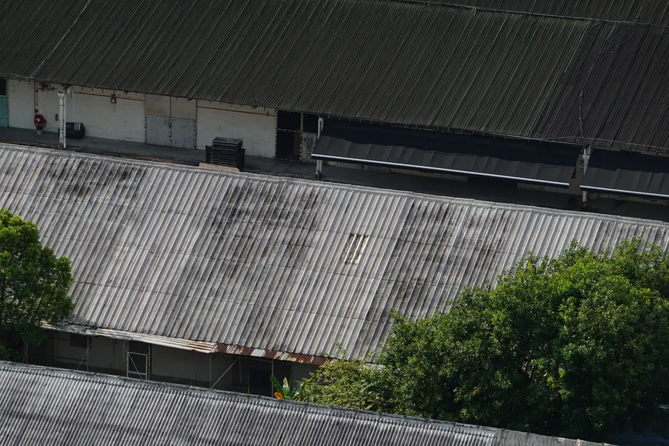 Oude golfplaatdaken op een rij loodsen, verweerd en donker uitgeslagen